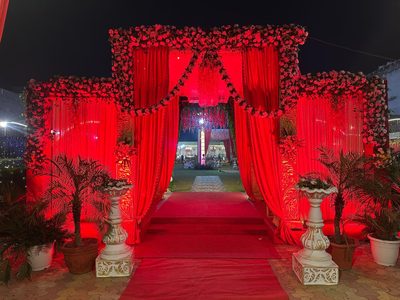 Red-lit floral welcome arch at night, Dharam Vatika wedding venue Sohna