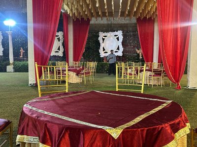 Round banquet table with gold chairs and red drapes at Dharam Vatika, Sohna Gurgaon
