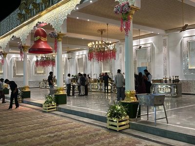 Buffet hall with floral chandeliers and guests at Dharam Vatika, Sohna Gurgaon